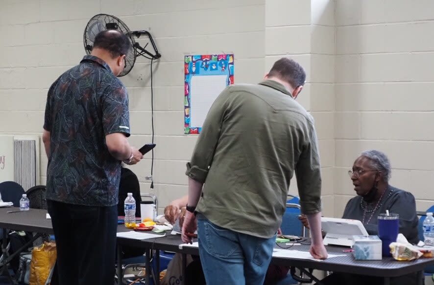 Two men at a table talking to a voting official.