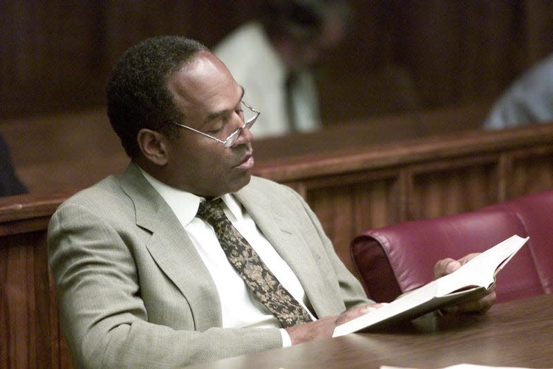 Former NFL star O.J. Simpson reads a book before the start of the third day of jury selection in a “road rage” trial October 11, 2001 in Miami, FL. - Photo: Wilfredo Lee (Getty Images)