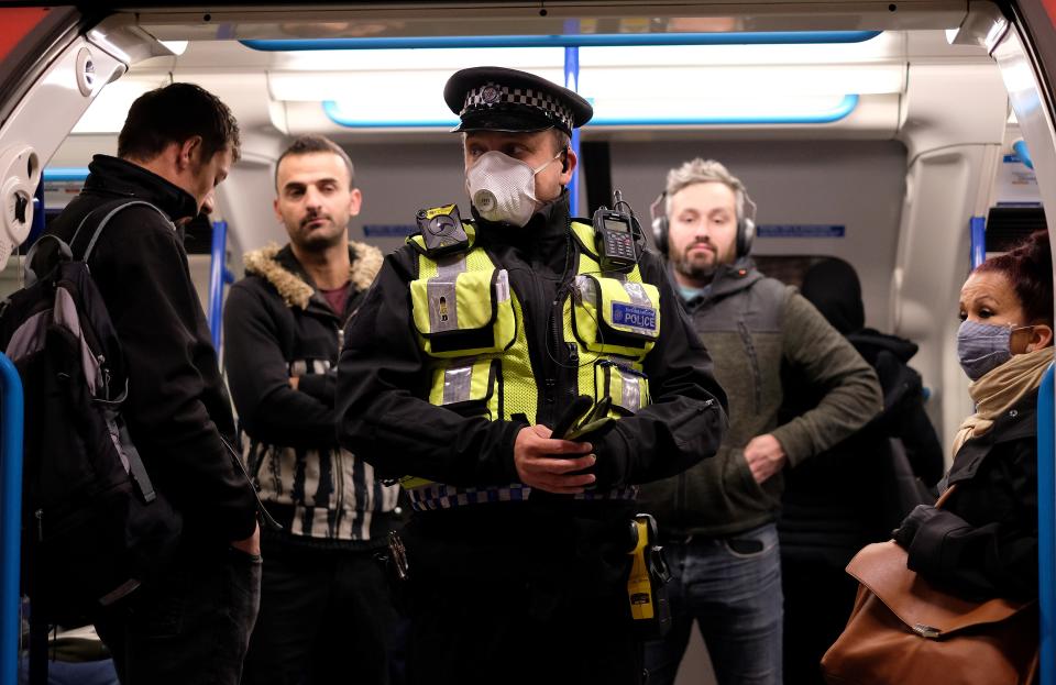 A police officer wearing PPE (personal protective equipment), including a face mask as a precautionary measure against COVID-19, stands with commuters as they travel in the morning rush hour on TfL (Transport for London) London underground Victoria Line trains from Finsbury Park towards central London on May 13, 2020, as people start to return to work after COVID-19 lockdown restrictions were eased. - Britain's economy shrank two percent in the first three months of the year, rocked by the fallout from the coronavirus pandemic, official data showed Wednesday, with analysts predicting even worse to come. Prime Minister Boris Johnson began this week to relax some of lockdown measures in order to help the economy, despite the rising death toll, but he has also stressed that great caution is needed. (Photo by Isabel INFANTES / AFP) (Photo by ISABEL INFANTES/AFP via Getty Images)