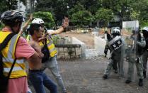 A shirtless anti-government protester is being prevented from confronting riot police officers during a protest at Tai Po district, in Hong Kong