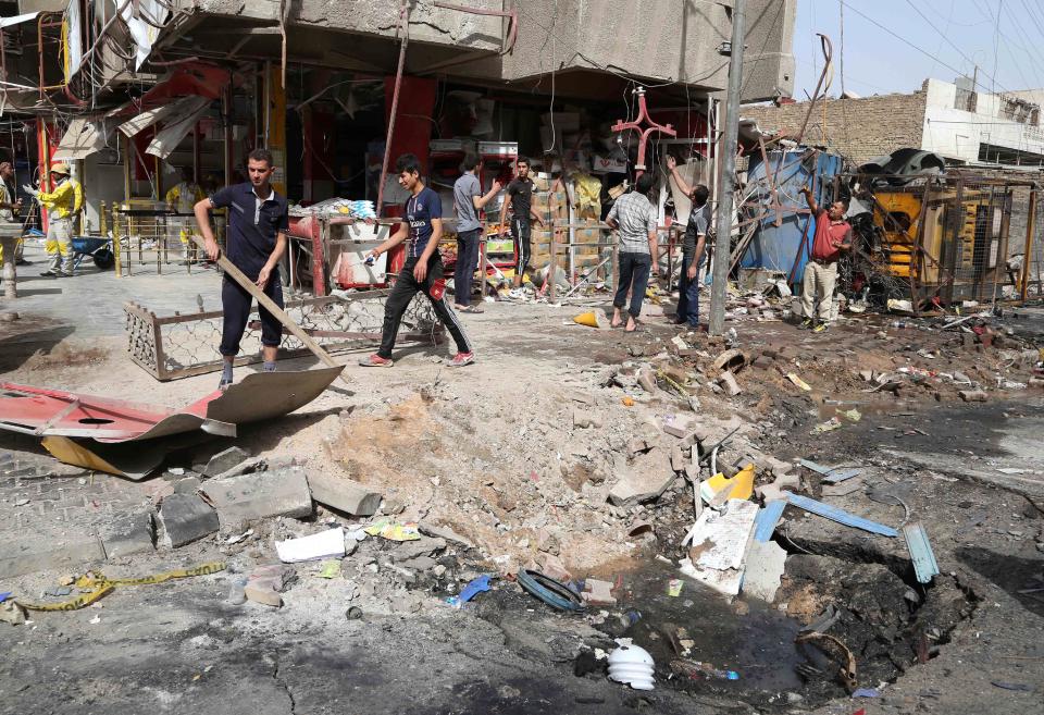 Iraqis sift through the aftermath of a car bomb attack in the crowded commercial area of Karrada, in Baghdad, Iraq, Friday, April 18, 2014. Authorities in Iraq say a car bomb targeted a street full of shoppers in the capital. in Baghdad on Thursday.(AP Photo/Karim Kadim)