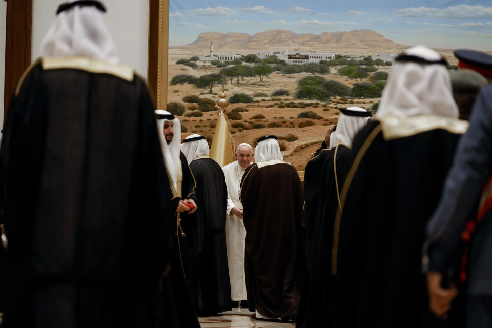El papa Francisco (al fondo) recibe la bienvenida de funcionarios de Bahrein el jueves 3 de noviembre de 2022, luego de aterrizar en la base aérea de el Sakhir. (AP Foto/Alessandra Tarantino)
