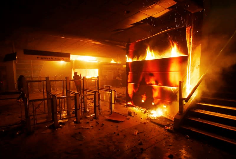 A subway ticket office is seen on fire during a protest against the increase in the subway ticket prices in Santiago