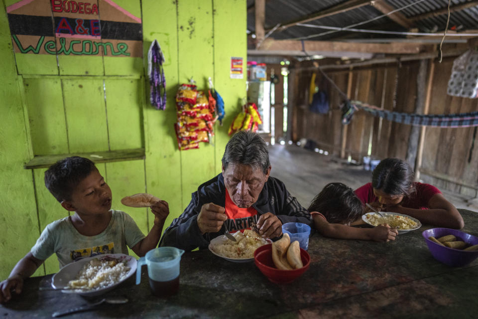 The Ochoa family, from left: Tommy, 4, Sebastian, 71, Iasnita, 7, and Ashley, 14, eat breakfast in their home in Sucusari, Peru, Thursday, May 30, 2024. In the community of thatched houses, the routine of the some 180 inhabitants is mostly traditional. They fish, hunt and grow fruit for local markets, mostly aguaje, an Amazon delicacy. (AP Photo/Rodrigo Abd)