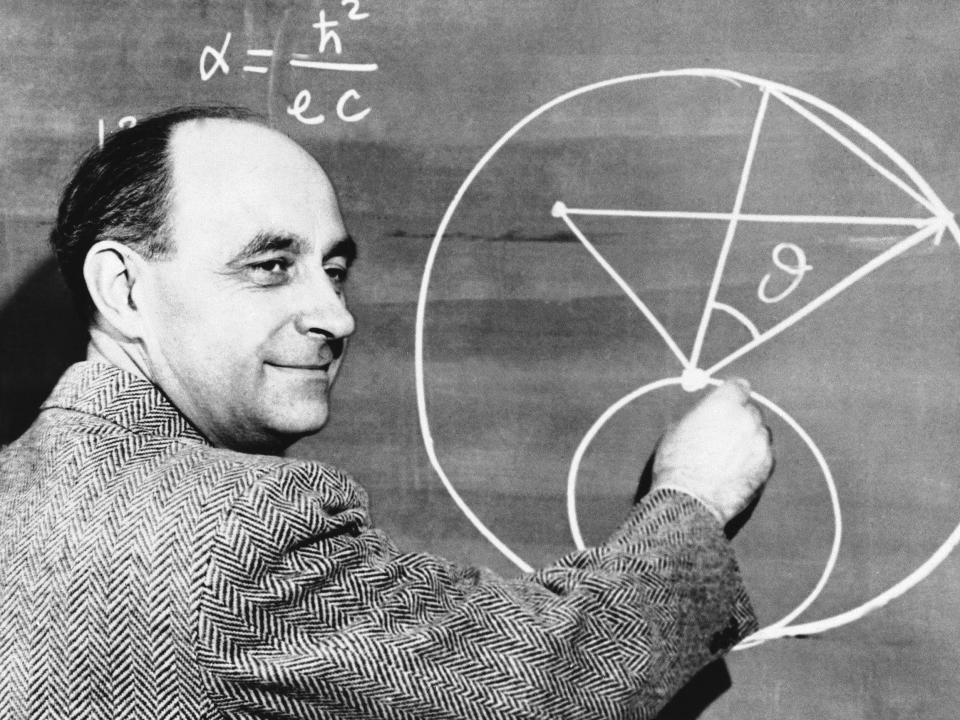 enrico fermi stands at a chalkboard drawing mathematical shapes