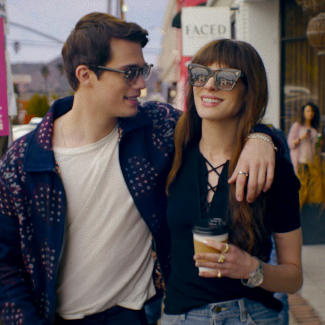  Nicholas Galitzine as Hayes Campbell and Anne Hathaway as Soléne, walking down a busy sidewalk as onlookers take pictures, in the rom-com 'The Idea of You'. 