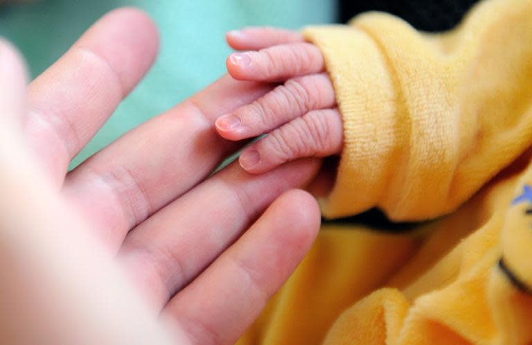 File photo shows a newborn baby taking the finger of his mother after delivery in a French hospital in September 2013.