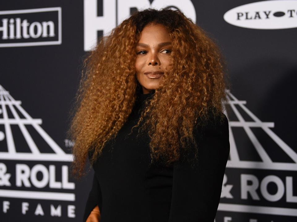 Janet Jackson poses for photographers. She wears a black turtleneck.