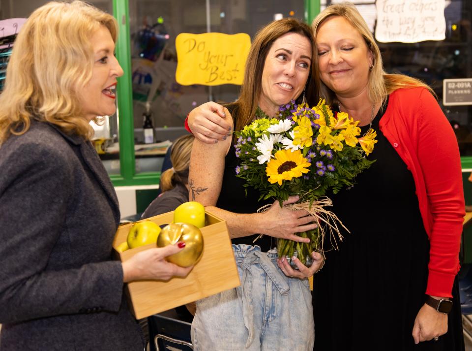 Maplewood Elementary School art teacher Jamie Roche, center, reacts as she is surprised by the Golden Apple Caravan on Friday. Superintendent of Schools Diane Gullett, left, surprises her with the Golden Apple as Principal Chrissy Carter, right, surprises her with flowers.