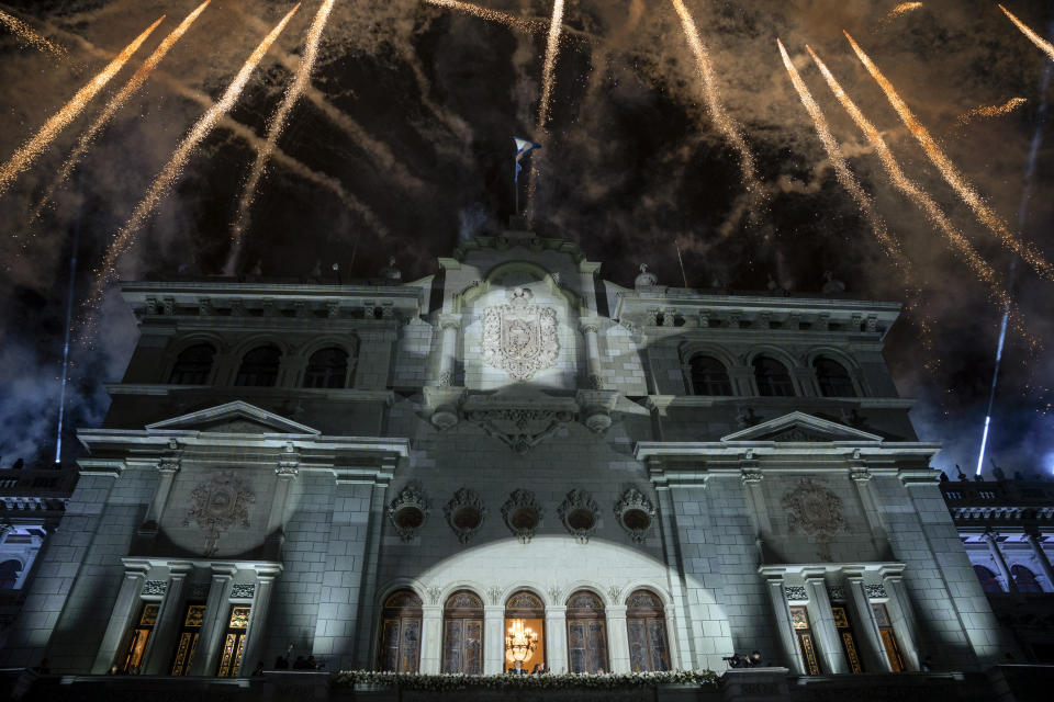 Fireworks explode over the National Palace as incoming Guatemalan President Bernardo Arévalo and Vice President Karin Herrera wave to supporters from the balcony, on their inauguration day in Guatemala City, early Jan. 15, 2024. (AP Photo/Santiago Billy)