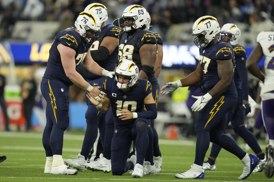 Los Angeles Chargers quarterback Justin Herbert (10) is helped up after being sacked and fumbling the ball by Baltimore Ravens linebacker Jadeveon Clowney during the second half of an NFL football game Sunday, Nov. 26, 2023, in Inglewood, Calif. (AP Photo/Ashley Landis)