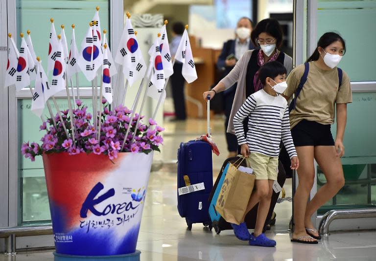 Passengers wearing face masks arrive at Gimpo international airport in Seoul, on June 17, 2015