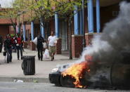 People with goods looted from a store walk near burning vehicles during clashes in Baltimore, Maryland April 27, 2015. REUTERS/Shannon Stapleton