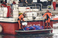 Italian firefighter divers bring ashore in a plastic bag the body of one of the victims of a shipwreck, in Porticello, Sicily, southern Italy, Thursday, Aug. 22, 2024. Divers searching the wreck of the superyacht Bayesian that sank off Sicily on Monday recovered a fifth body on Thursday and continued to search for one more as investigators sought to learn why the vessel sank so quickly. (AP Photo/Salvatore Cavalli)