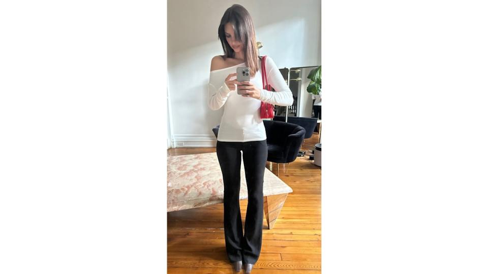 Emily Ratajkowski poses for a mirror selfie in a white long sleeve and black trousers