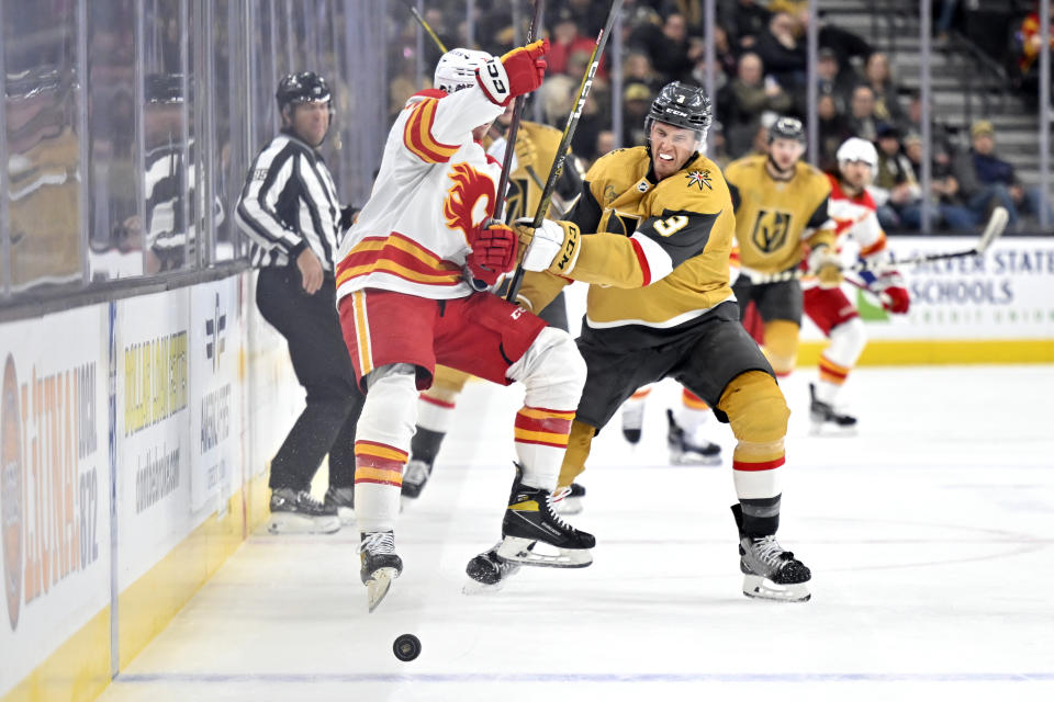 Calgary Flames right wing Walker Duehr, front left, and Vegas Golden Knights defenseman Brayden McNabb battle for the puck during the first period of an NHL hockey game Thursday, Feb. 23, 2023, in Las Vegas. (AP Photo/David Becker)