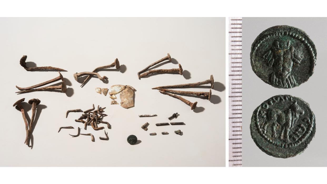  The content of the primary cremation grave, including: burnt remains of a bone artifact, bent nails, shards of broken glass, and a second century A.D. coin from southern Turkey. Scale in centimeters. 