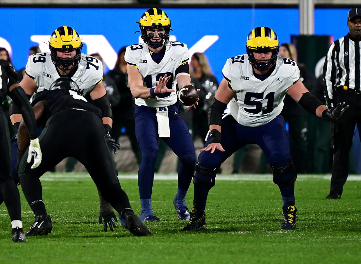 Michigan Wolverines quarterback Jack Tuttle takes a snap from Michigan Wolverines Greg Crippen in the fourth quarter against the Michigan State Spartans at Spartan Stadium.