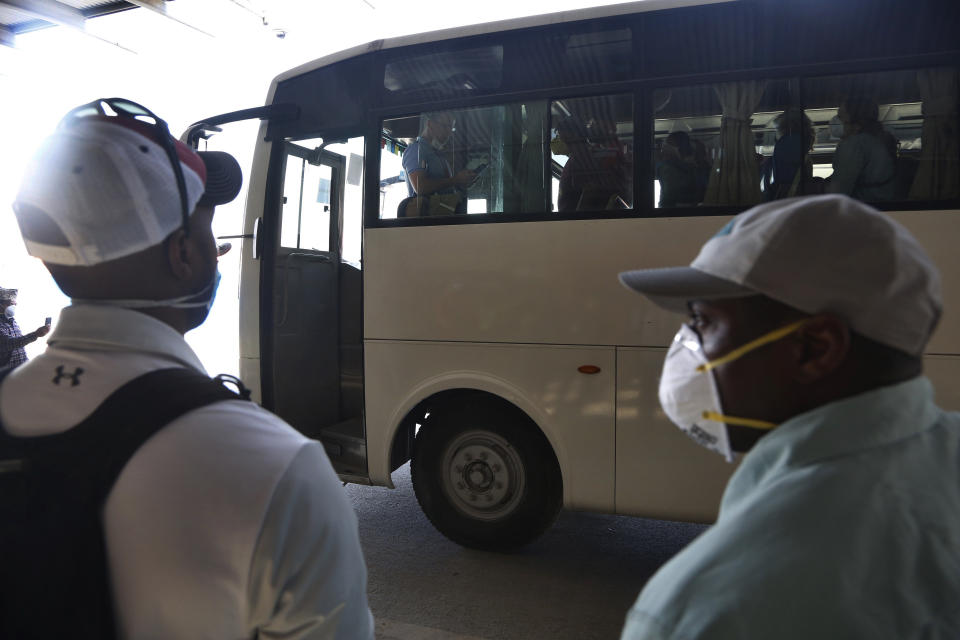 A U.S. embassy staff, gives instructions to passengers inside a bus carrying American citizens as they arrive to board a Qatar Airways flight at the Tribhuvan International Airport in Kathmandu, Nepal, Tuesday, March 31, 2020. Several American citizens are stranded in Nepal due to the nationwide lockdown enforced in an attempt to stop the coronavirus spread. The new coronavirus causes mild or moderate symptoms for most people, but for some, especially older adults and people with existing health problems, it can cause more severe illness or death. (AP Photo/Niranjan Shrestha)