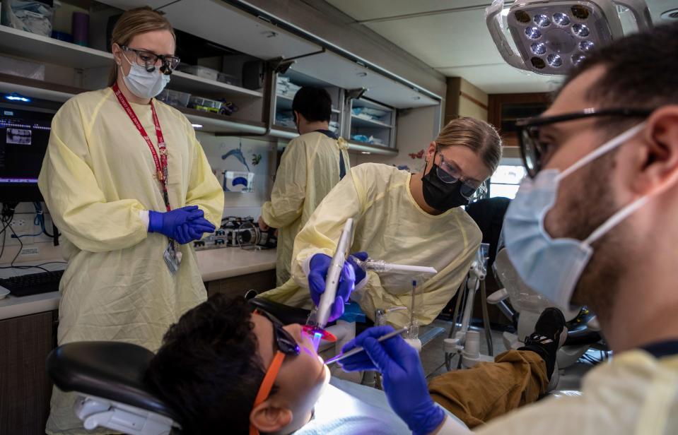 Stephanie Lica, a clinical instructor with the Titans for Teeth Mobile Clinic, watches Grace Monette, a third-year dental student at the University of Detroit Mercy School of Dentistry Dental Clinic, perform a fissure sealant on 9-year-old Philip Martinez-Rivera inside the mobile clinic at the Munger Elementary-Middle School in Detroit on April 26, 2023.