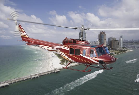 A red Textron Bell Huey II helicopter in flight