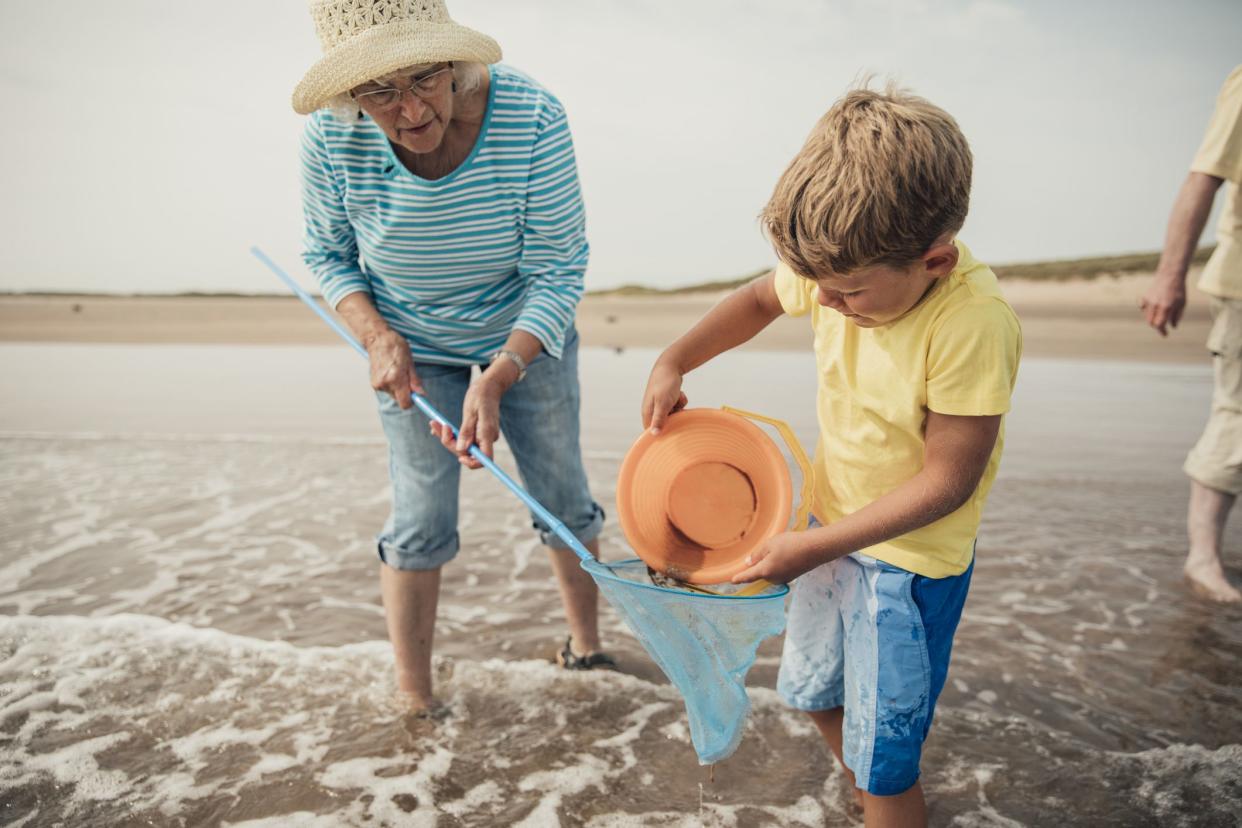 Searching for sea artifacts with a bucket and fishing rod at the beach with grandma.