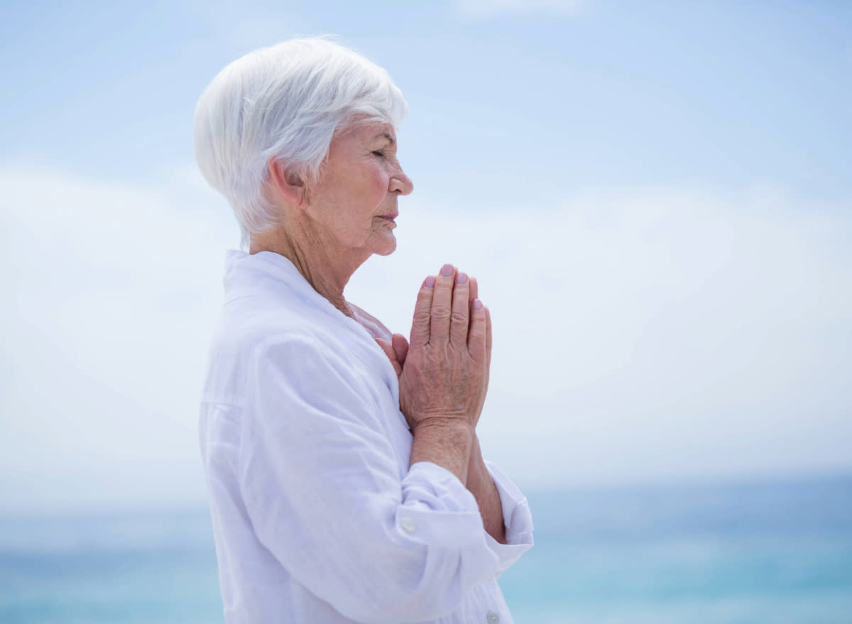 senior woman meditating outdoors by the beach