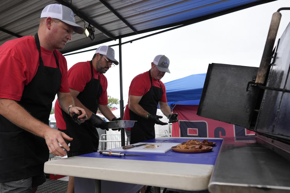 Members of the Pig Diamonds BBQ Team, Brent Little, left, Adriano Pedro, center, and John Borden, right, prepare a sample of whole hog for judges at the World Championship Barbecue Cooking Contest, Saturday, May 18, 2024, in Memphis, Tenn. The international team is comprised of members from Brazil and the United States. (AP Photo/George Walker IV)