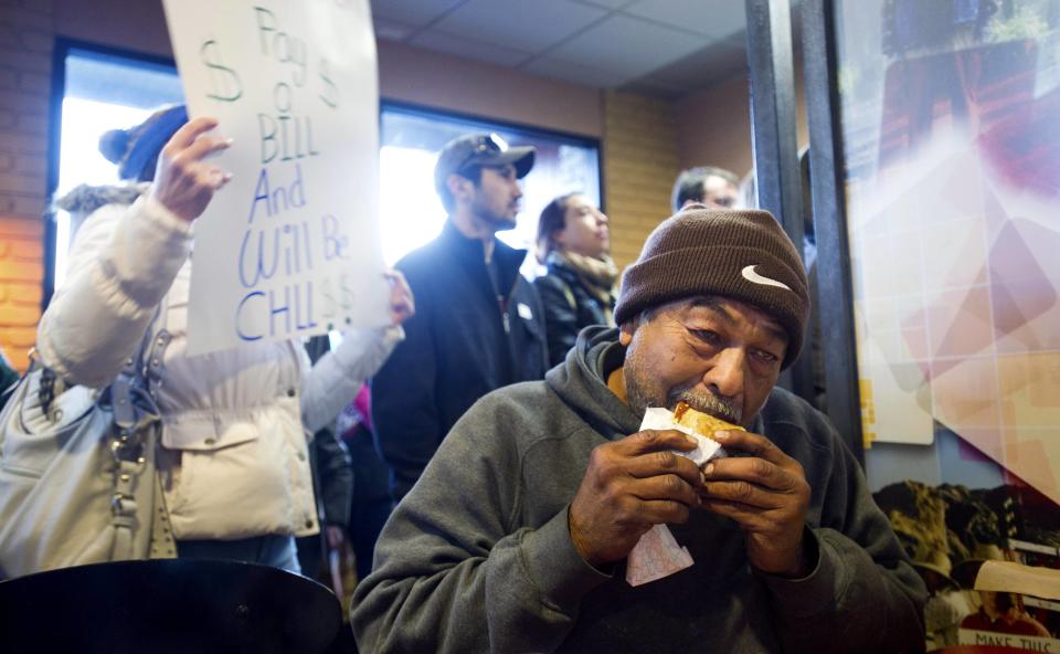 Hernandez eats dinner at Jack in The Box fast food outlet while demonstrators demanding an increase in worker wages block the order counter in Oakland