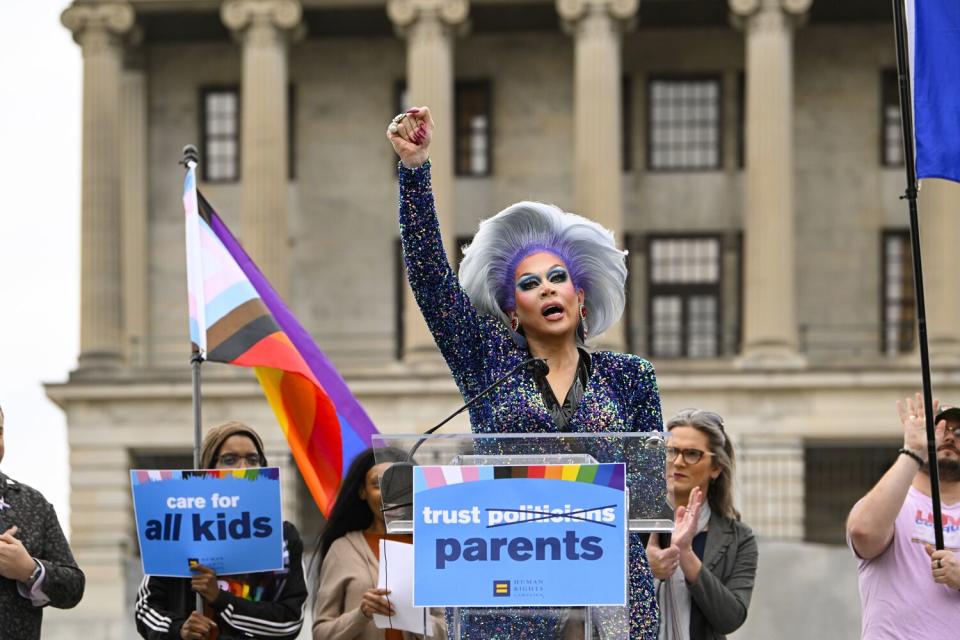 A person raises their right fist at a lectern outdoors.