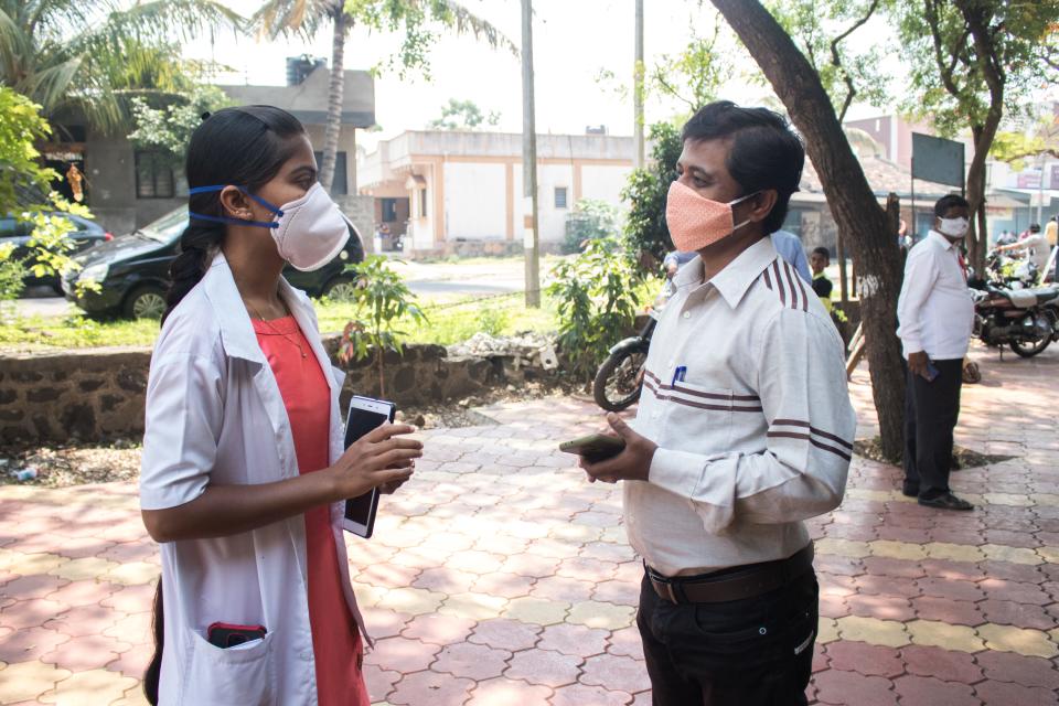 Community health officer Seema Koli, left, addresses a villager's question about the COVID-19 vaccine near the health center in Tardal, India.