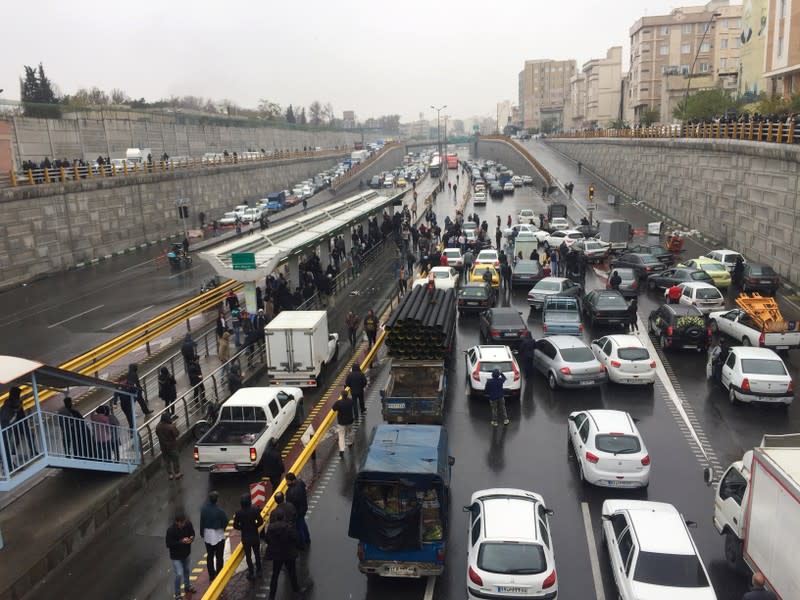 People stop their cars on a highway to protest against increased gas price in Tehran