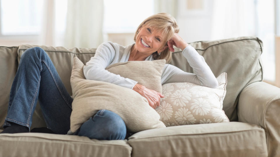 A woman relaxing on a couch holding pillow who is stress-free thanks to vagus nerve exercises