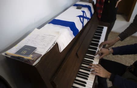 An immigrant's certificate and a passport are seen on top of a piano as newly arrived immigrants from France play it at Ulpan Etzion, the original residential school and absorption centre, which has taught Hebrew to tens of thousands of immigrants since 1949, in Jerusalem January 20, 2015. REUTERS/Ronen Zvulun