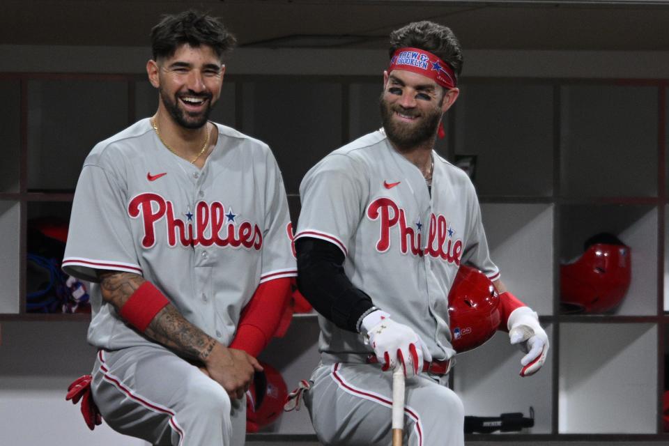 Philadelphia Phillies right fielder Nick Castellanos, left, and designated hitter Bryce Harper, smile in the dugout during a game against the San Diego Padres on June 23.