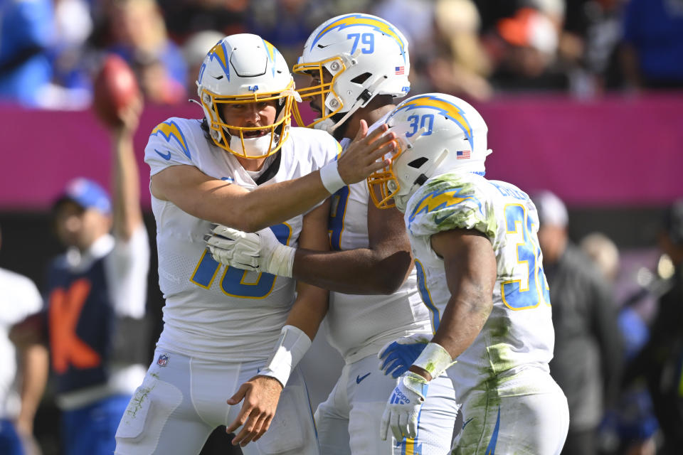 Los Angeles Chargers running back Austin Ekeler (30) is congratulated by quarterback Justin Herbert (10) after running in for a touchdown against the Cleveland Browns during the second half of an NFL football game, Sunday, Oct. 9, 2022, in Cleveland. Offensive tackle Trey Pipkins III is at center. (AP Photo/David Richard)