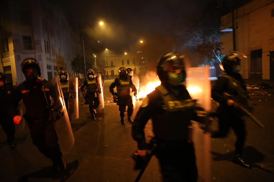 Police walk past burning barricades in order to take position to disperse protesters, near Congress where lawmakers swore-in a new president after voting to oust President Martin Vizcarra the day before, in Lima, Peru, Tuesday, Nov. 10, 2020. Peru swore in businessman and head of Congress Manuel Merino Tuesday who is unknown to most and was recently accused of trying to secure the military’s support for a congressional effort to boot the nation’s last leader out over unproven corruption allegations. (AP Photo/Rodrigo Abd)