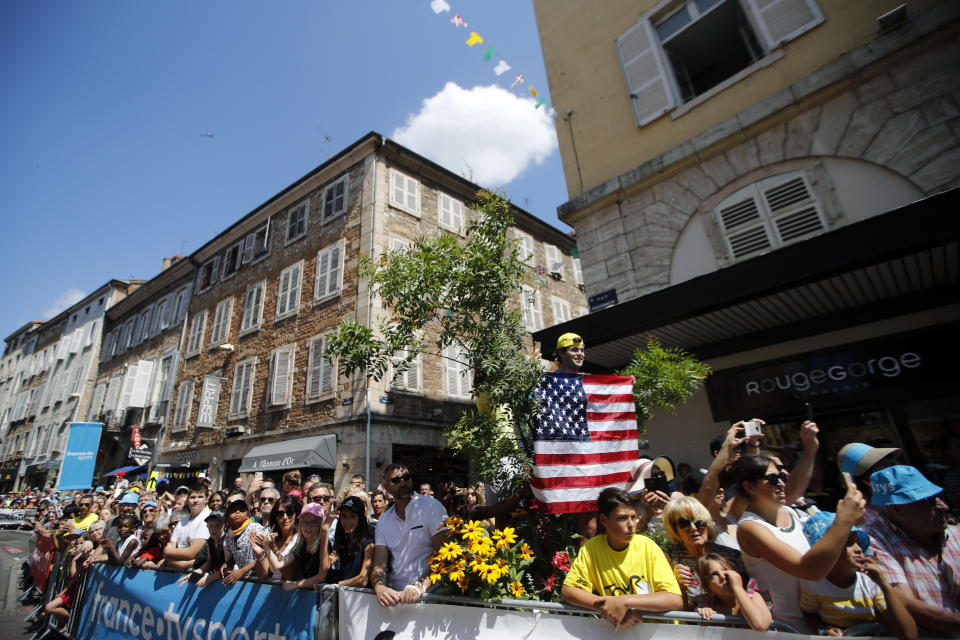 A spectator holds a U.S flag as he cheers riders during the eighth stage of the Tour de France cycling race over 200 kilometers (125 miles) with start in Macon and finish in Saint Etienne, France, Saturday, July 13, 2019. (AP Photo/Christophe Ena)