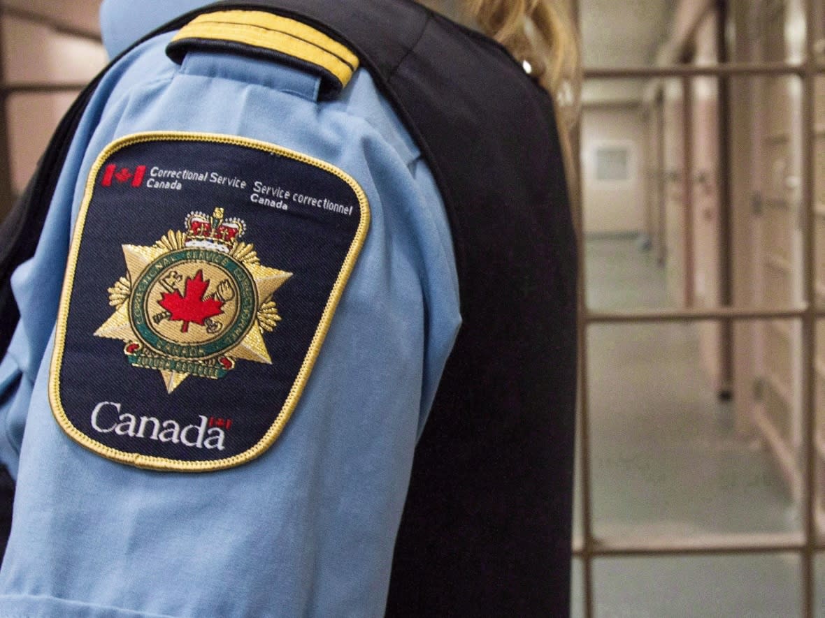 A Correctional Service of Canada badge is seen on the arm of a uniform in this photo. The service is named in a lawsuit launched by a federal inmate who alleges he received substandard care for his bad back while in custody at various prisons.  ( Lars Hagberg/Canadian Press - image credit)