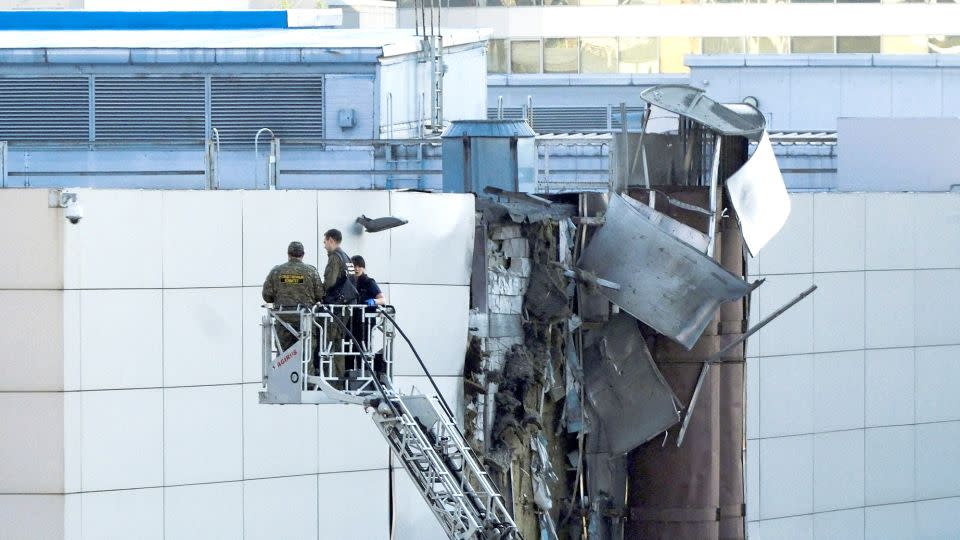 Investigators work near a damaged roof following a reported shooting down of a drone in Moscow, Russia. - Shamil Zhumatov/Reuters