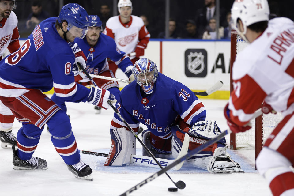 New York Rangers goaltender Jonathan Quick (32) looks on as Jacob Trouba (8) clears the puck in front of Detroit Red Wings center Dylan Larkin, right, during the third period of an NHL hockey game Tuesday, Nov. 7, 2023, in New York. The Rangers won 5-3. (AP Photo/Adam Hunger)