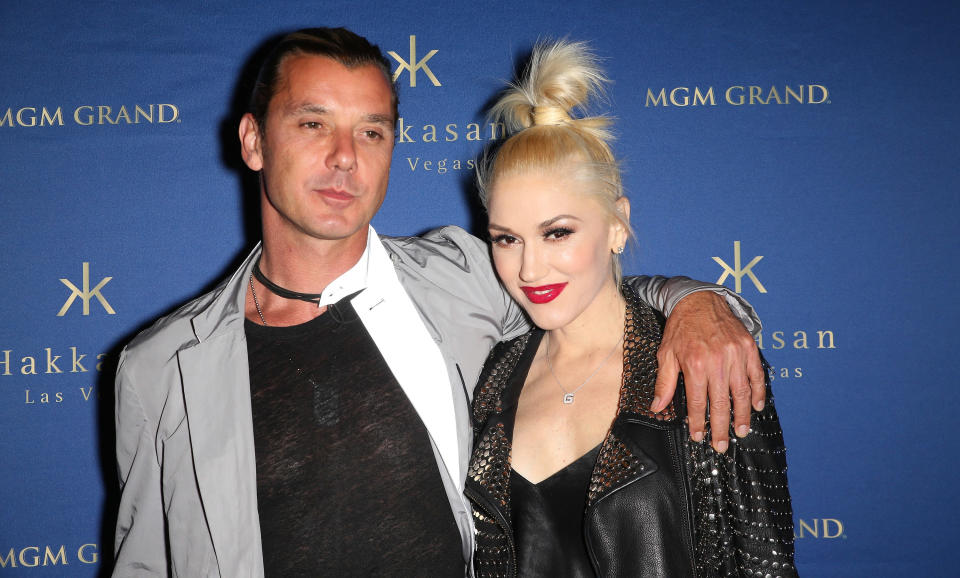 Gavin Rossdale wearing a gray jacket and black shirt while putting an arm around Gwen Stefani who is in all black