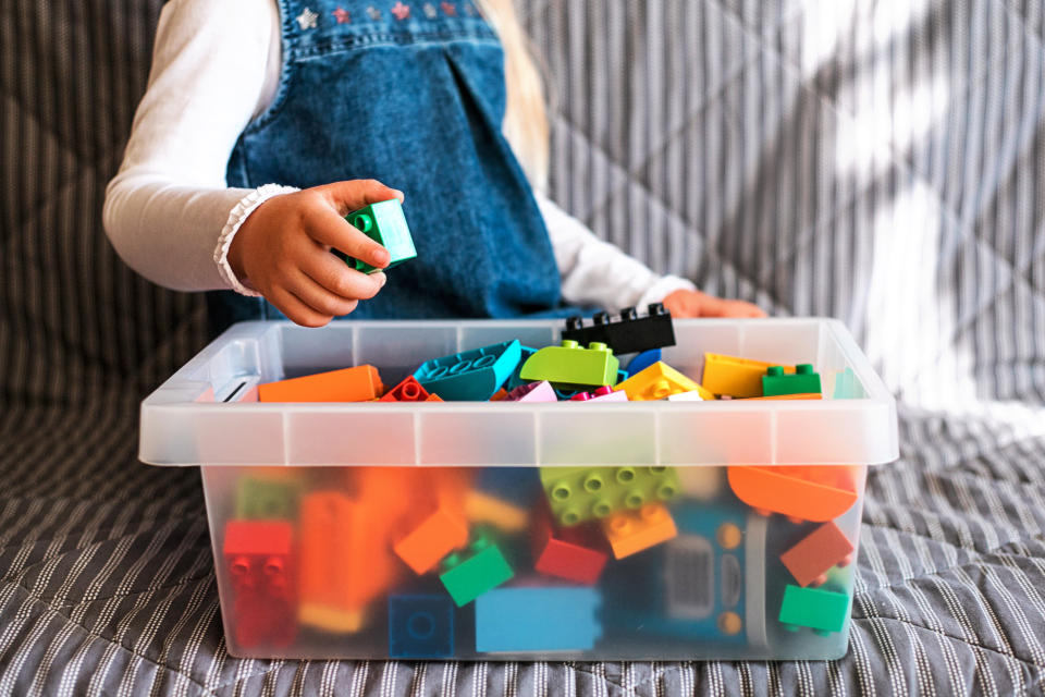 A little girl putting Legos away