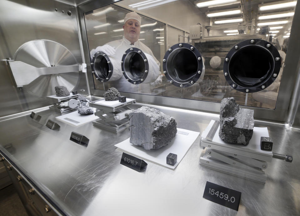 Ryan Zeigler, Apollo sample curator, left, stands next to a nitrogen-filled case displaying various lunar samples collected during Apollo missions 15, 16 and 17, inside the lunar lab at the NASA Johnson Space Center Monday, June 17, 2019, in Houston. (AP Photo/Michael Wyke)