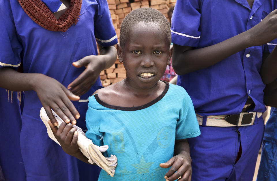 In this photo taken Tuesday, March 26, 2019, a young boy stands with a group of school children as they welcome donors who were launching a new joint education in emergencies initiative with the aim of providing daily meals to 75,000 children, in Aweil, Northern Bahr el Ghazal state, in South Sudan. Human rights activist Mia Farrow spoke to The Associated Press as she visited South Sudan again in her new role as envoy for the International Rescue Committee, helping the aid group to promote a global initiative to change the way humanitarian organizations approach malnutrition. (AP Photo/Sam Mednick)