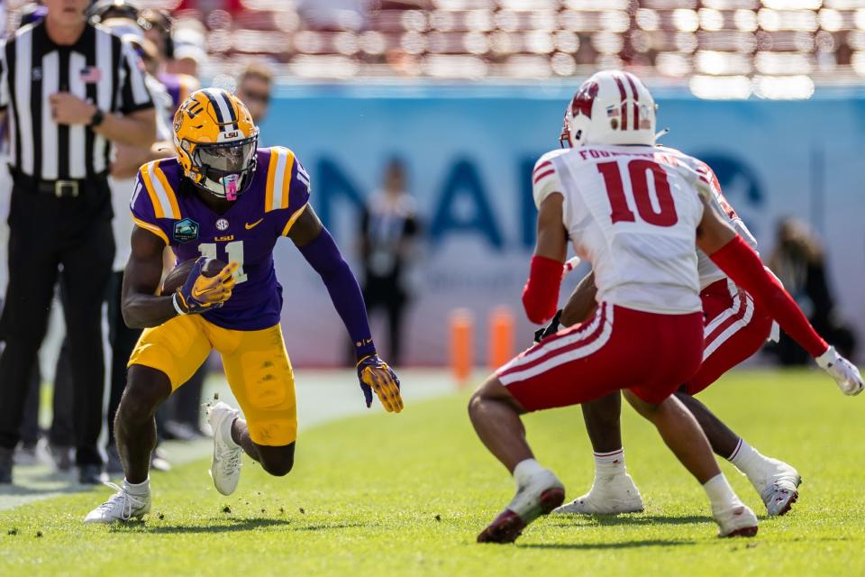 Jan 1, 2024; Tampa, FL, USA; LSU Tigers wide receiver Brian Thomas Jr. (11) runs with the ball towards Wisconsin Badgers cornerback Nyzier Fourqurean (10) during the first half at Raymond James Stadium. Mandatory Credit: Matt Pendleton-USA TODAY Sports