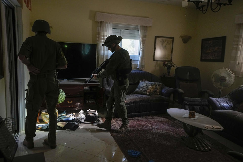 Israeli soldiers inspect a house damaged by Hamas militants in Kibbutz Be'eri, Israel, Saturday, Oct. 14, 2023. The kibbutz was overrun by Hamas militants from the nearby Gaza Strip on Oct. 7, when they killed and captured many Israelis. Two weeks after Hamas militants gunned down 10 percent of their community, torturing scores of people and kidnapping many back to Gaza, the Israeli government has relocated half the kibbutz to the upscale David Resort, a hotel-turned-refugee camp. (AP Photo/Ariel Schalit, File)