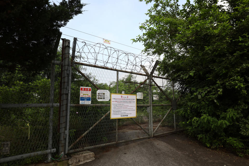 A barbed wire fence and gate with signs written in Korean.