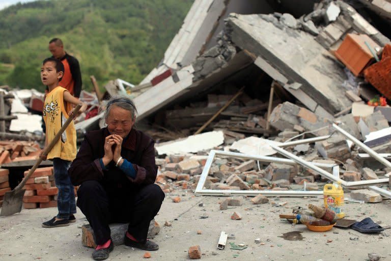 An elderly woman is seen offering prayers outside her destroyed home, two days after a powerful earthquake, in Ya'an, Sichuan province, on April 21, 2013