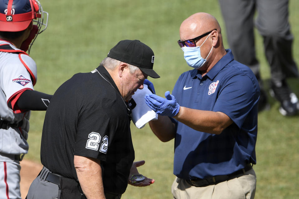 Home plate umpire Joe West (22) is tended to by a Washington Nationals trainer after he was injured during the first inning of a baseball game between the Toronto Blue Jays and the Nationals, Thursday, July 30, 2020, in Washington. (AP Photo/Nick Wass)